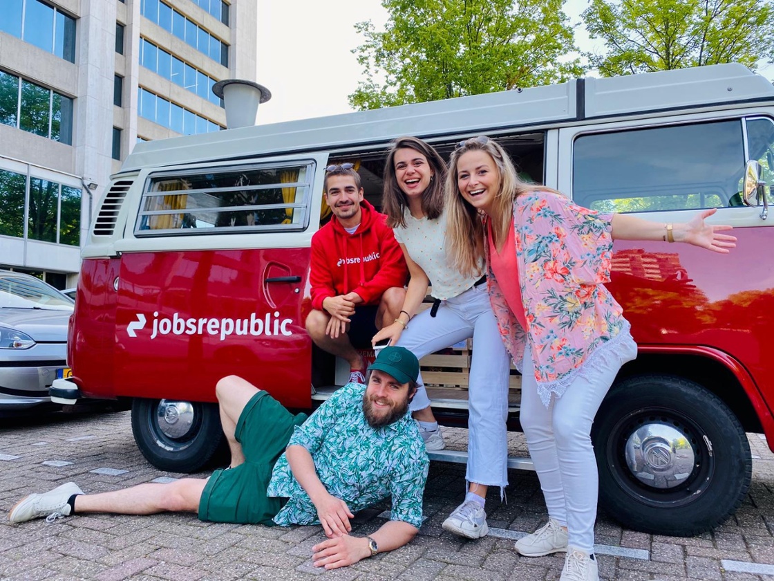 Vier mensen uit het Jobsrepublic team naast een busje