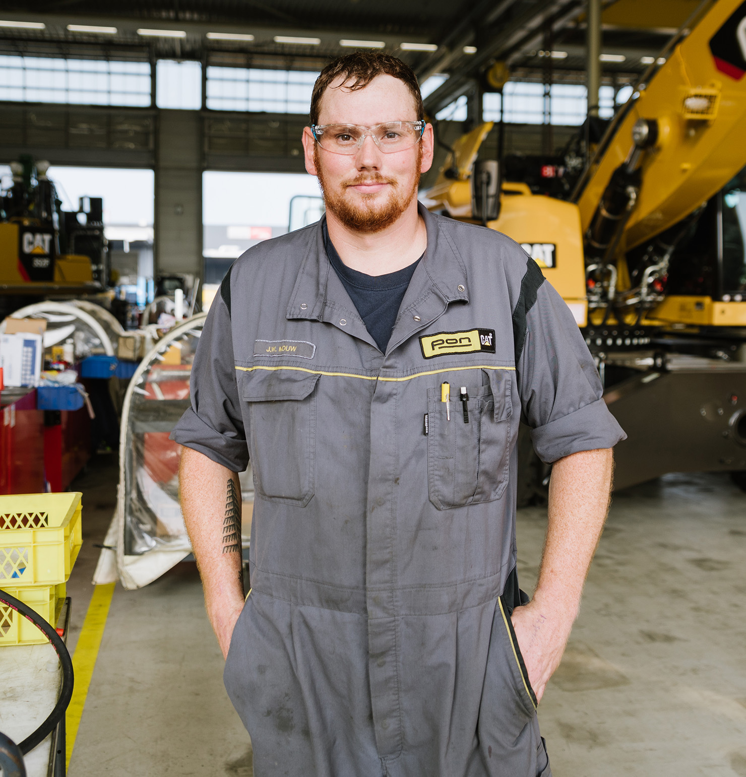 Man staat voor graafmachine in PON werkplaats