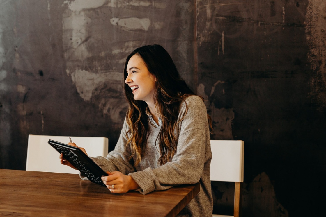 Lachende vrouw aan tafel met een tablet